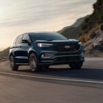 A black 2024 Ford Edge is shown driving.