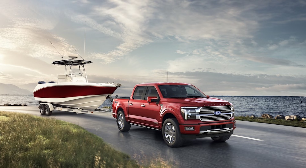 A red 2024 Ford F-150 is shown towing a boat.