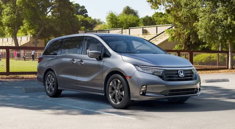 A silver 2024 Honda Odyssey is shown parked near a soccer match after visiting a used Honda dealer.