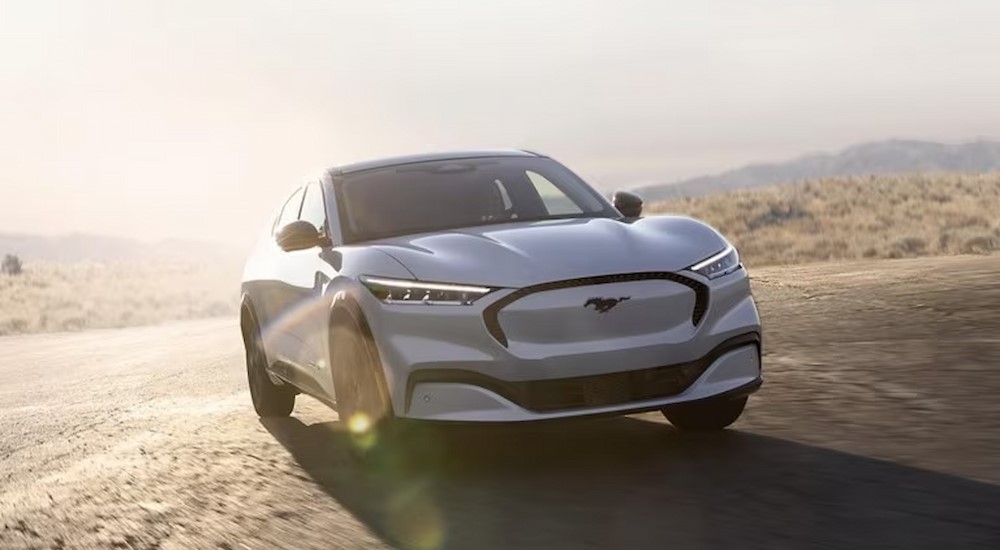 A white 2024 Ford Mustang Mach-E is shown driving off-road.