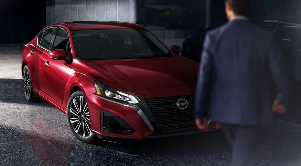 A red 2024 Nissan Altima SL is shown parked next to a person wearing a blue jacket.