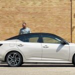 A white 2024 Nissan Sentra is shown parked near a hotel.