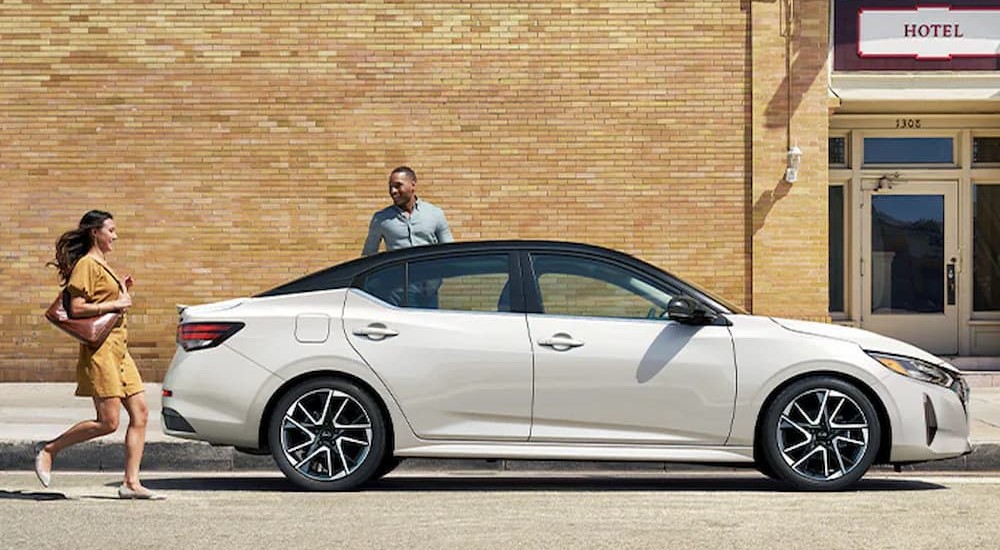 A white 2024 Nissan Sentra is shown parked near a hotel.