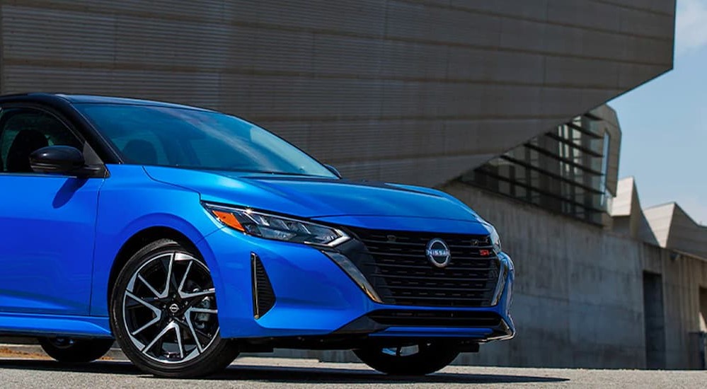 A blue 2024 Nissan Sentra SR is shown parked near a building.