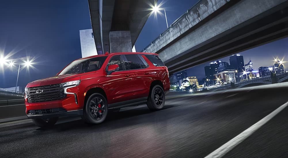 A red 2024 Chevy Tahoe is shown driving in a city.