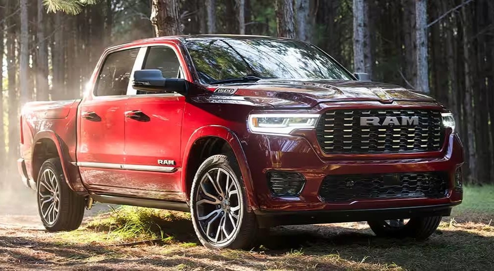 A red 2024 RAM 1500 is shown parked off-road in a forest.