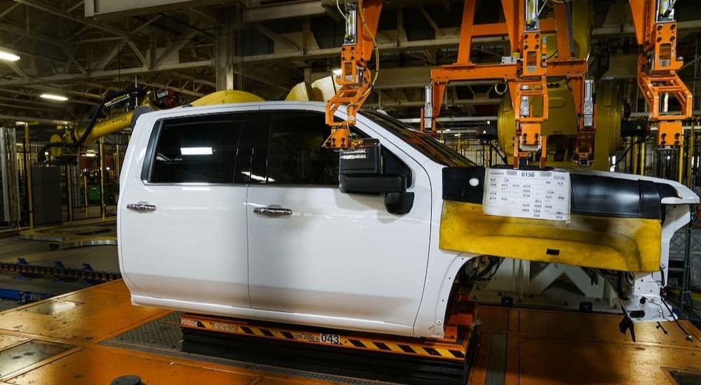 The crew cab of a white Chevy Silverado is shown on a production line.