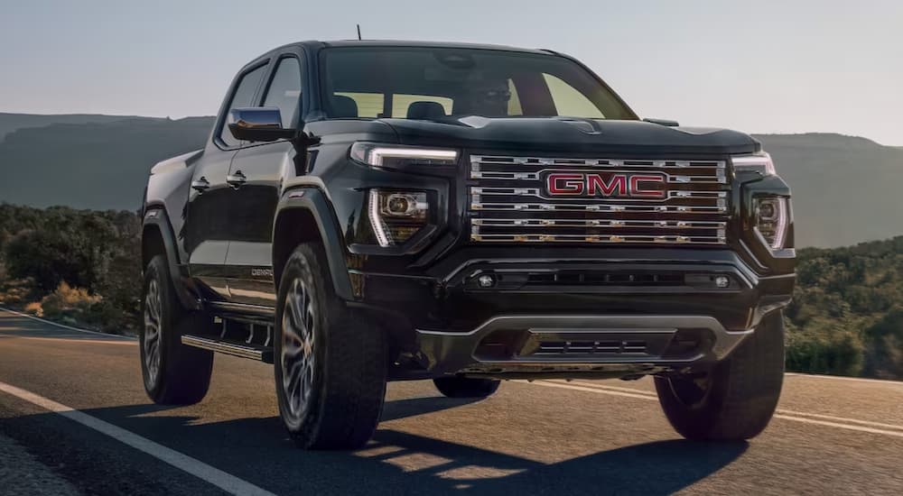 A black 2023 GMC Canyon Denali is shown on an open road near a GMC dealer.