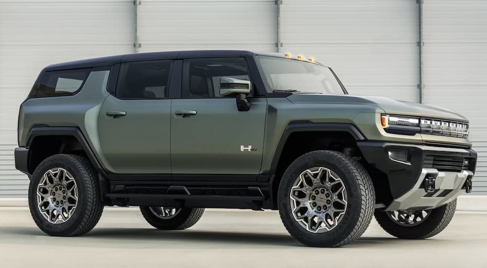A green 2024 GMC Hummer EV is shown from the side parked in an empty lot.