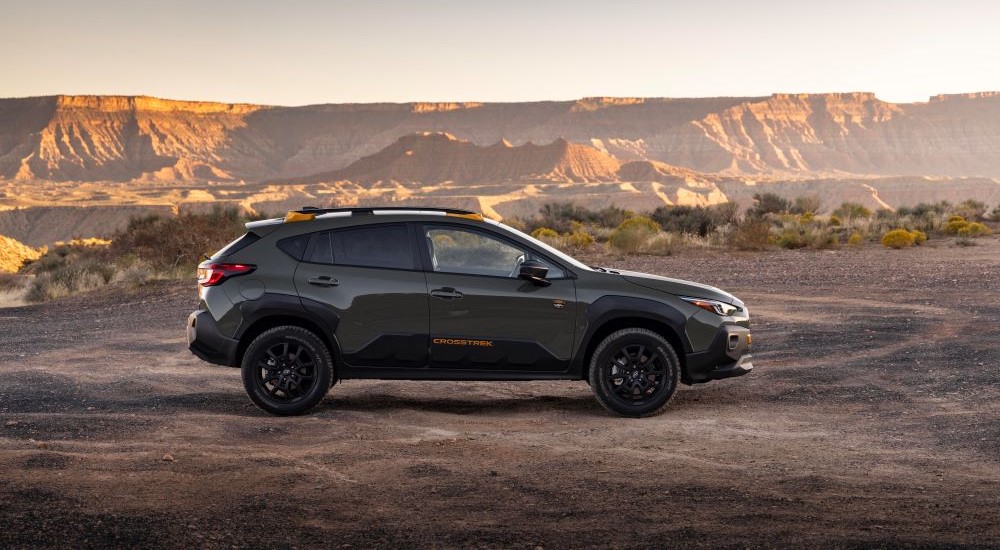 A grey 2024 Subaru Crosstrek Wilderness is shown from the side parked on dirt lot.