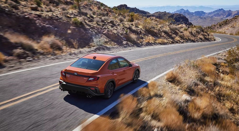 An orange 2024 Subaru WRX Limited is shown driving on an open road after leaving a Subaru dealer near you.