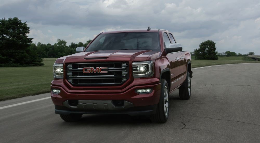 A red 2016 GMC Sierra 1500 All-Terrain is shown driving on a road.