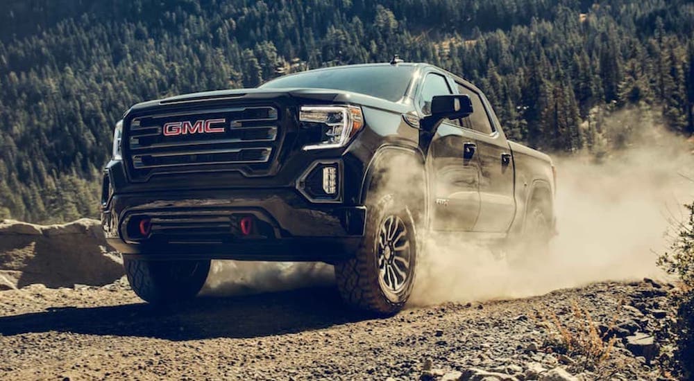 A popular used GMC Sierra 1500 for sale, a black 2020 GMC Sierra 1500, is shown driving off-road.