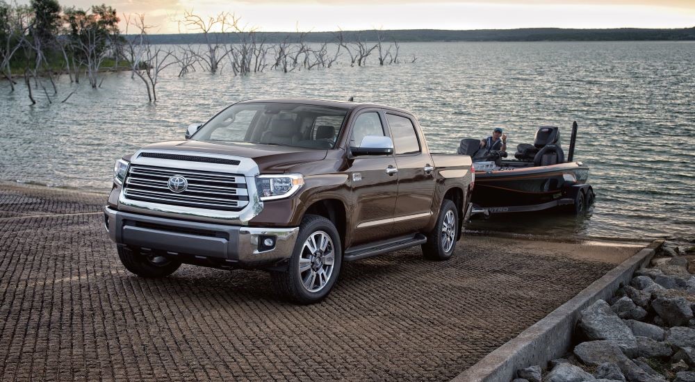 A brown 2020 Toyota Tundra s shown towing a boat near water.