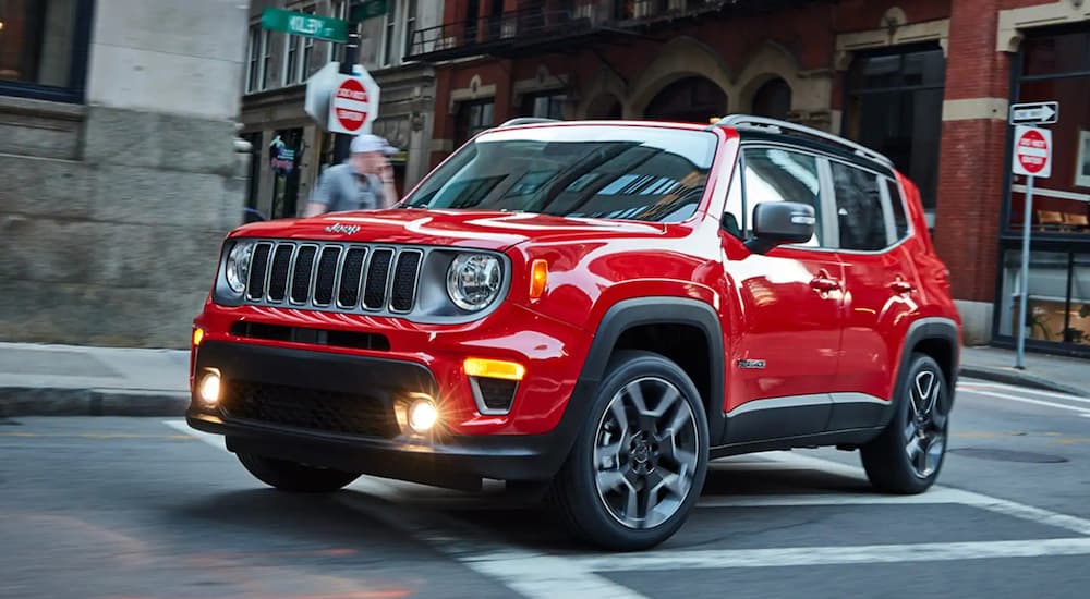 A red 2021 Jeep Renegade is shown driving in a city after visiting a used Jeep dealership.