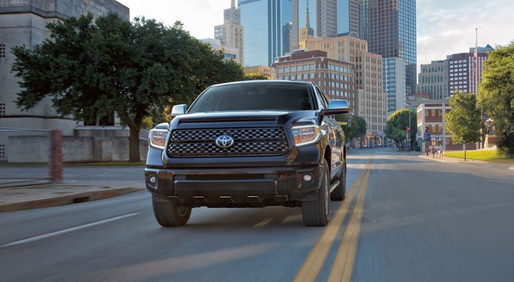 A black 2021 Toyota Tundra is shown driving on a city street after viewing used trucks for sale.