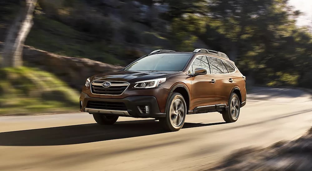 A brown 2022 Subaru Outback Touring is shown driving on a dirt road.