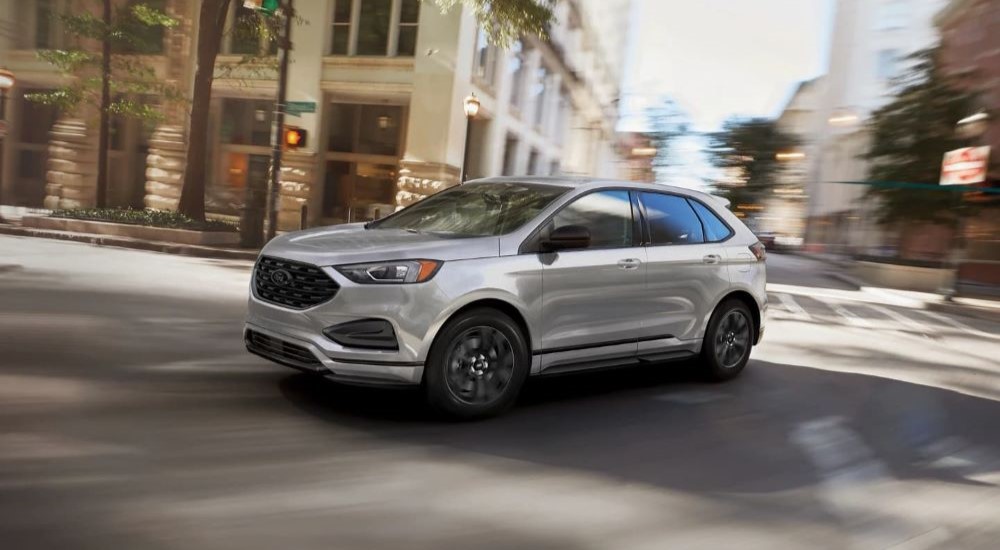 A silver 2023 Ford Edge is shown driving on a city street.