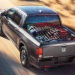 A gray 2023 Honda Ridgeline RTL-E is shown driving off-road to view used trucks for sale.