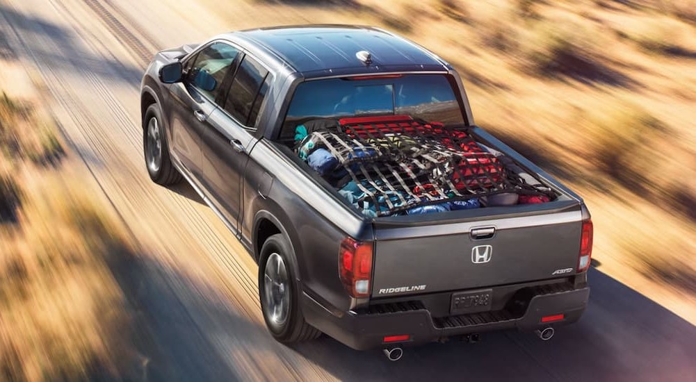 A gray 2023 Honda Ridgeline RTL-E is shown driving off-road to view used trucks for sale.