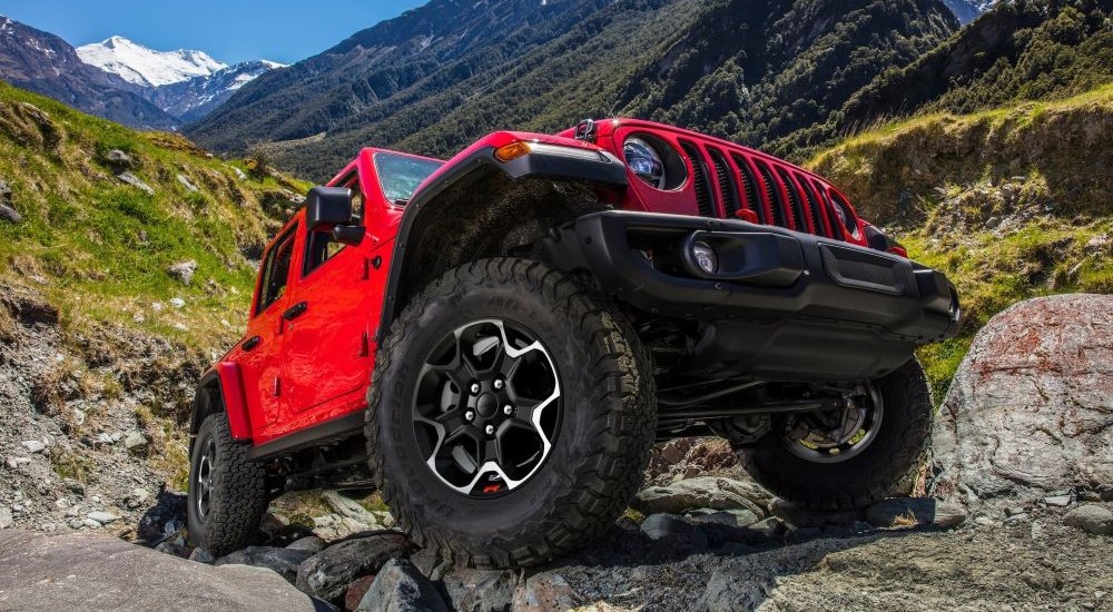 A red 2023 Jeep Wrangler Unlimited is shown driving off-road.