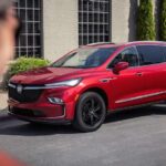 A red 2024 Buick Enclave Sport Touring is shown paked on the side of a street.