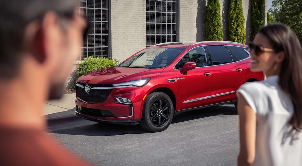 A red 2024 Buick Enclave Sport Touring is shown paked on the side of a street.