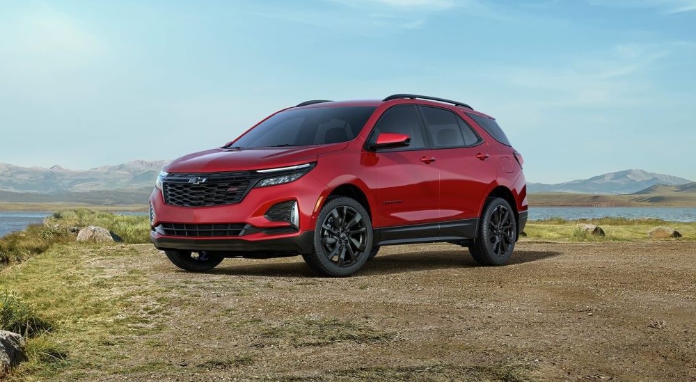 A red 2024 Chevy Equinox RS is shown parked near a lake after a 2024 Chevy Equinox vs 2024 Nissan Rogue comparison.