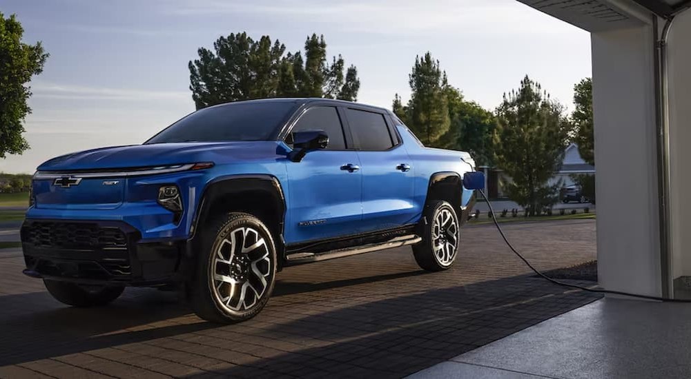 A blue 2024 Chevy Silverado EV RST is shown parked and charging.