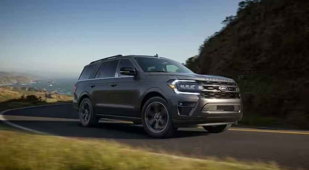 A gray 2024 Ford Expedition Platinum MAX is shown driving on a road near a beach.