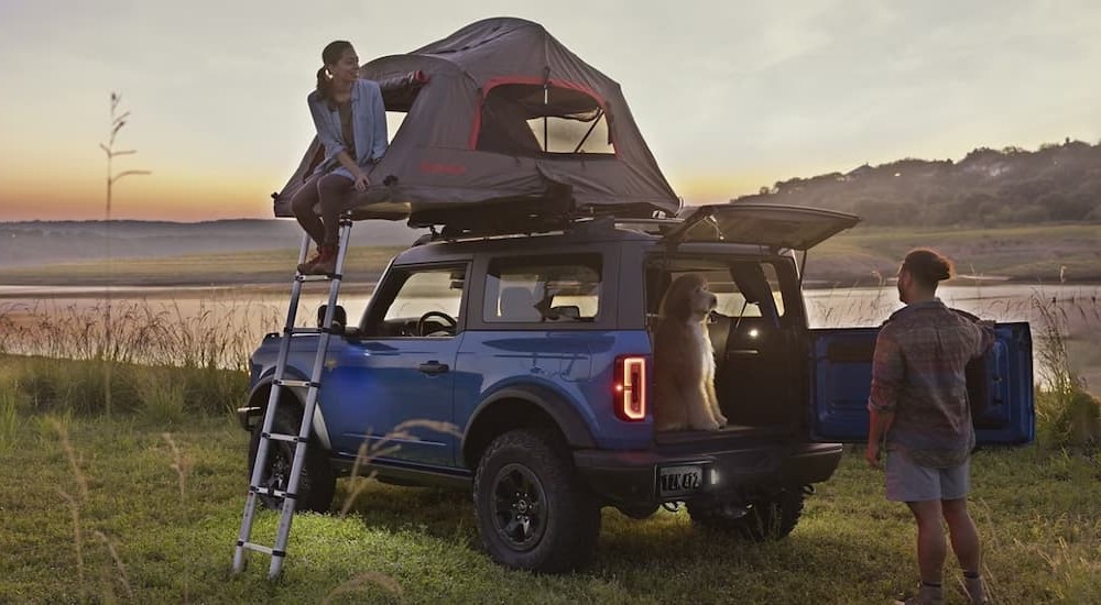 A blue 2024 Ford Bronco is shown parked near a pond.