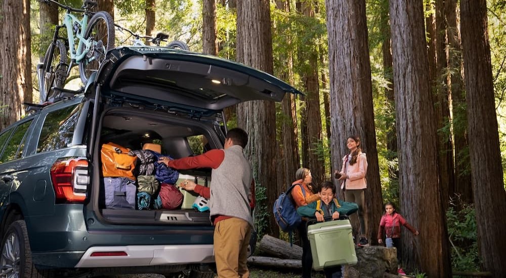A blue 2024 Ford Expedition is shown parked near a family.