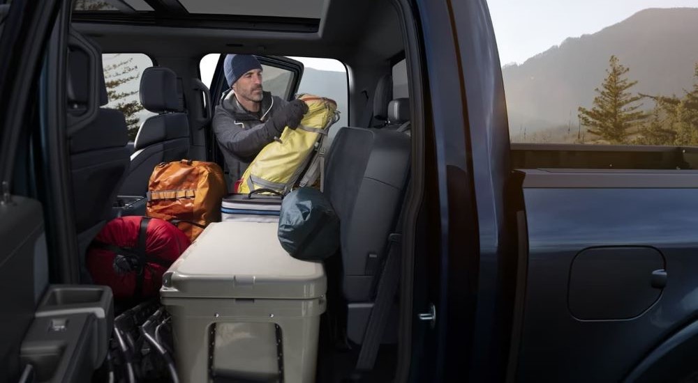 A person is shown loading equipment onto the backseat of a 2024 Ford F-150 Platinum.