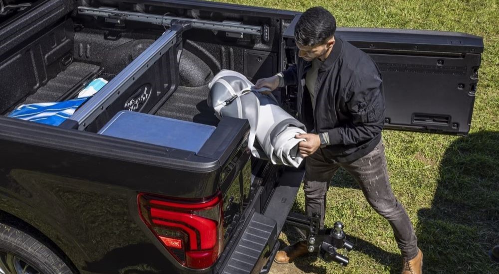 A person is shown off-loading equipment from the bed of a black 2024 Ford F-150.