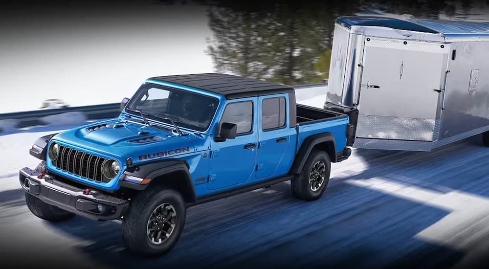 A blue 2024 Jeep Gladiator Rubicon is shown towing a trailer.