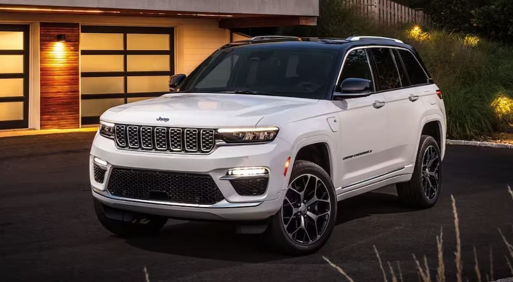 A white 2024 Jeep Grand Cherokee for sale is shown parked on a driveway.