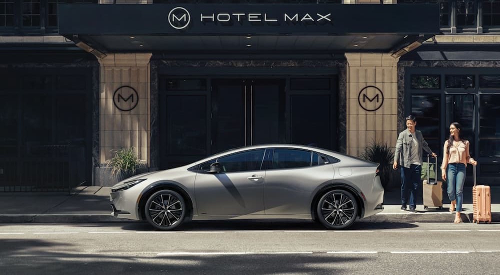 A silver 2024 Toyota Prius Limited AWD is shown parked near a hotel close to a used Toyota dealer.