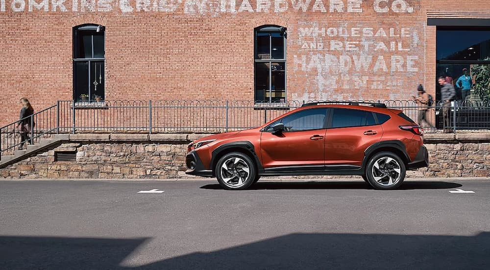 An orange 2024 Subaru Crosstrek for sale is shown parked near a building.