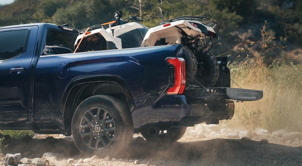 A blue 2024 Toyota Tundra is shown carrying an ATV in the bed.