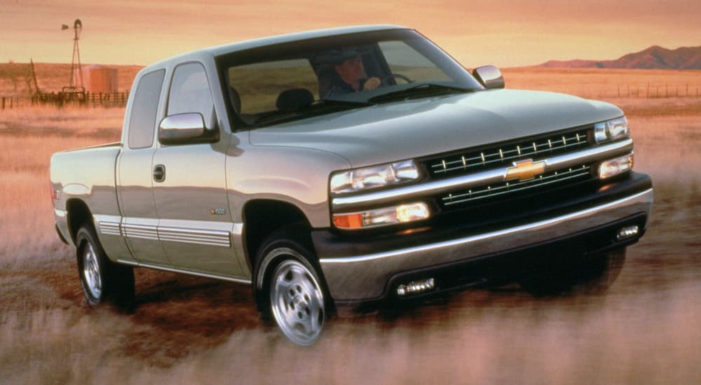 A tan 2002 Chevy Silverado 1500 is shown driving through a field.