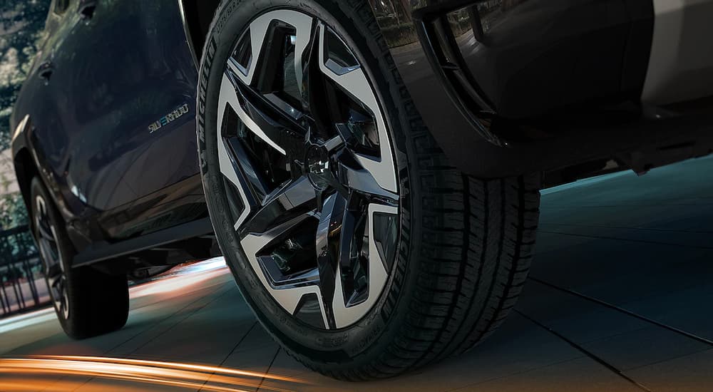 A close up shows the wheels on a dark blue 2024 Chevy Silverado EV.