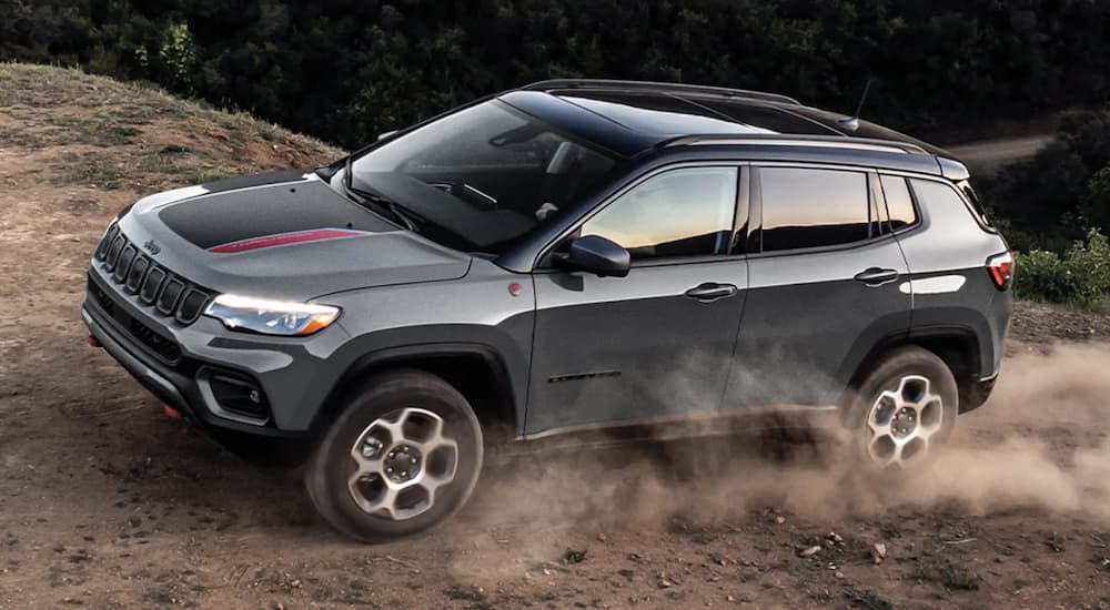 A grey 2023 Jeep Compass is shown off-roading in a desert.