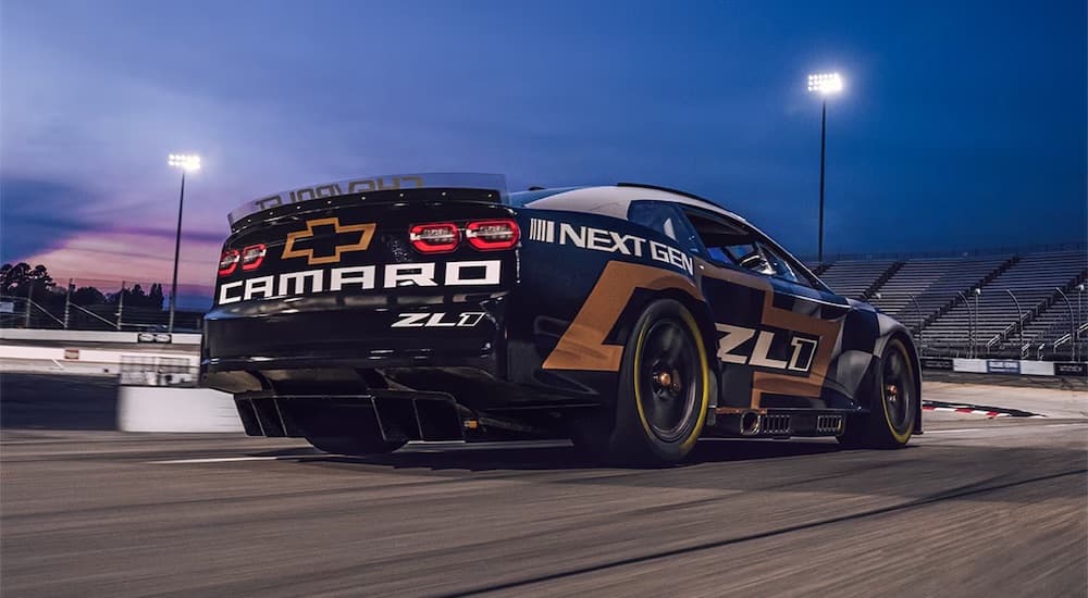 A black, white and yellow 2021 Chevrolet NASCAR Next Gen Camaro ZL1 is shown racing from the rear.