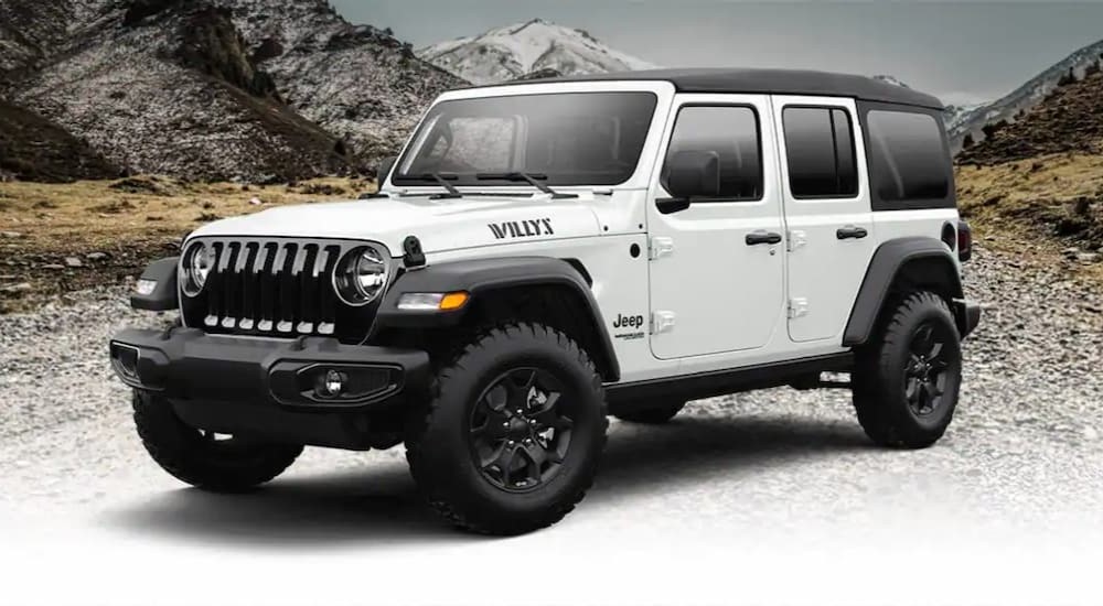 A white 2022 Jeep Wrangler Willy Sport is shown parked off-road on snow.