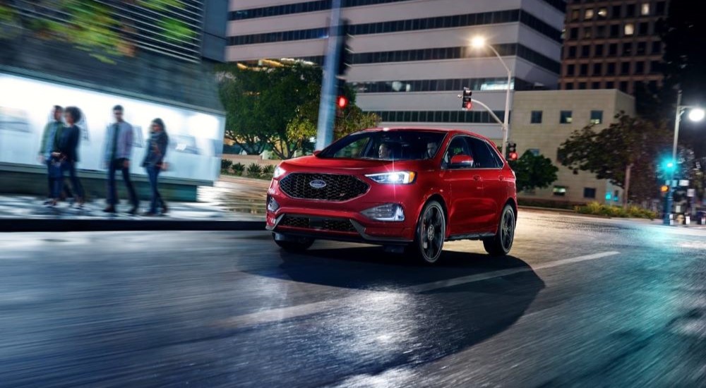 A red 2023 Ford Edge ST is shown driving in a city.