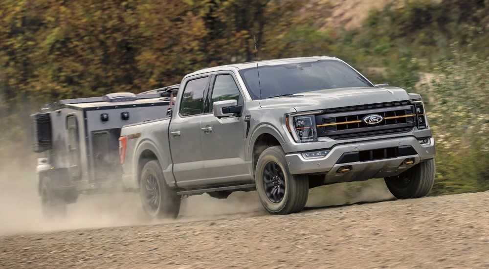 A silver 2023 Ford F-150 Tremor is shown towing a trailer.