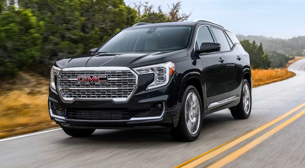 A black 2024 GMC Terrain Denali is shown driving.