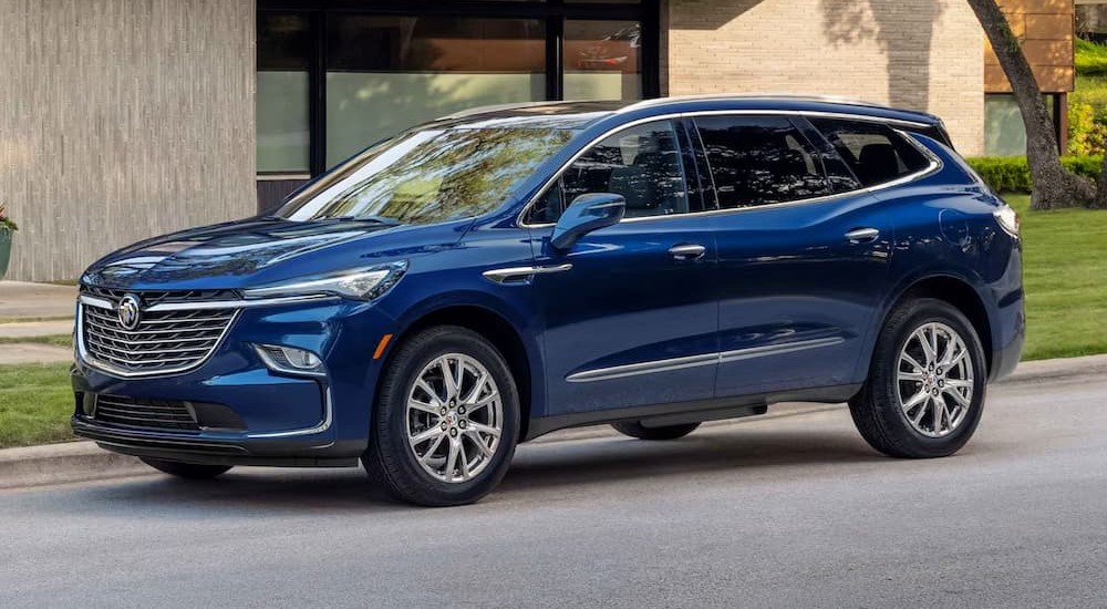 A blue 2024 Buick Enclave is shown parked near a Buick dealer.