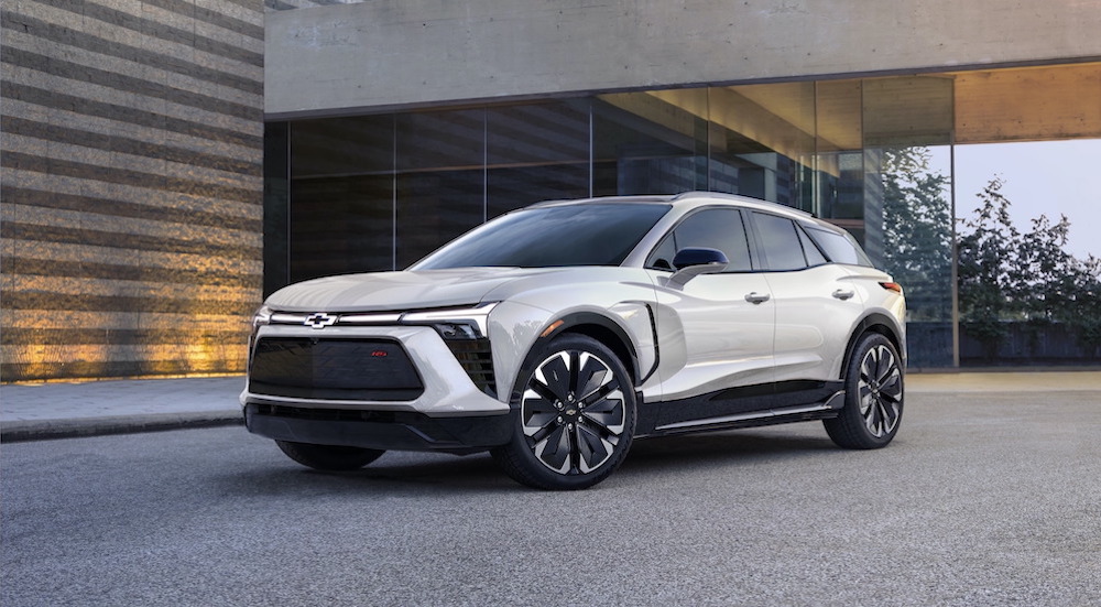 A white 2024 Chevy Blazer EV is shown parked near a Chevy dealer.