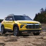 A yellow 2024 Chevy Trailblazer ACTIV is shown parked off-road near a lake.